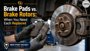 Close-up of worn brake pads and scored brake rotors on a vehicle being inspected at an auto repair shop in New Port Richey Florida